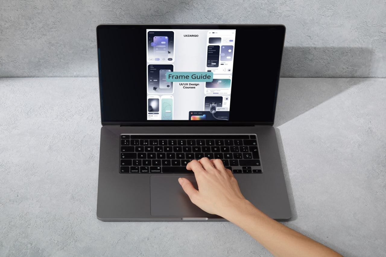 Person using a laptop on a gray surface with a focus on the screen displaying an app interface.